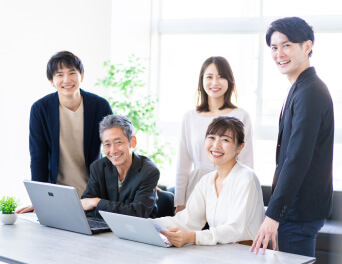 オフィスで笑顔で集まる5人のビジネスパーソン